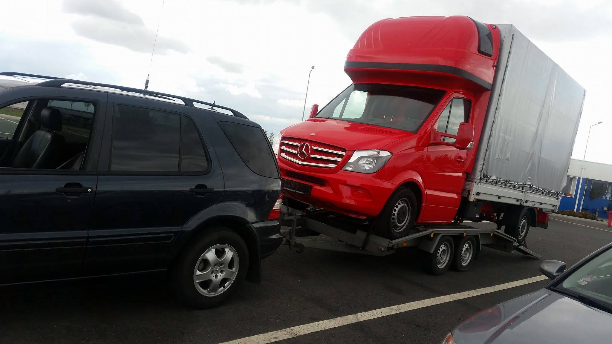 Autoutilitară roșie transportată pe platformă